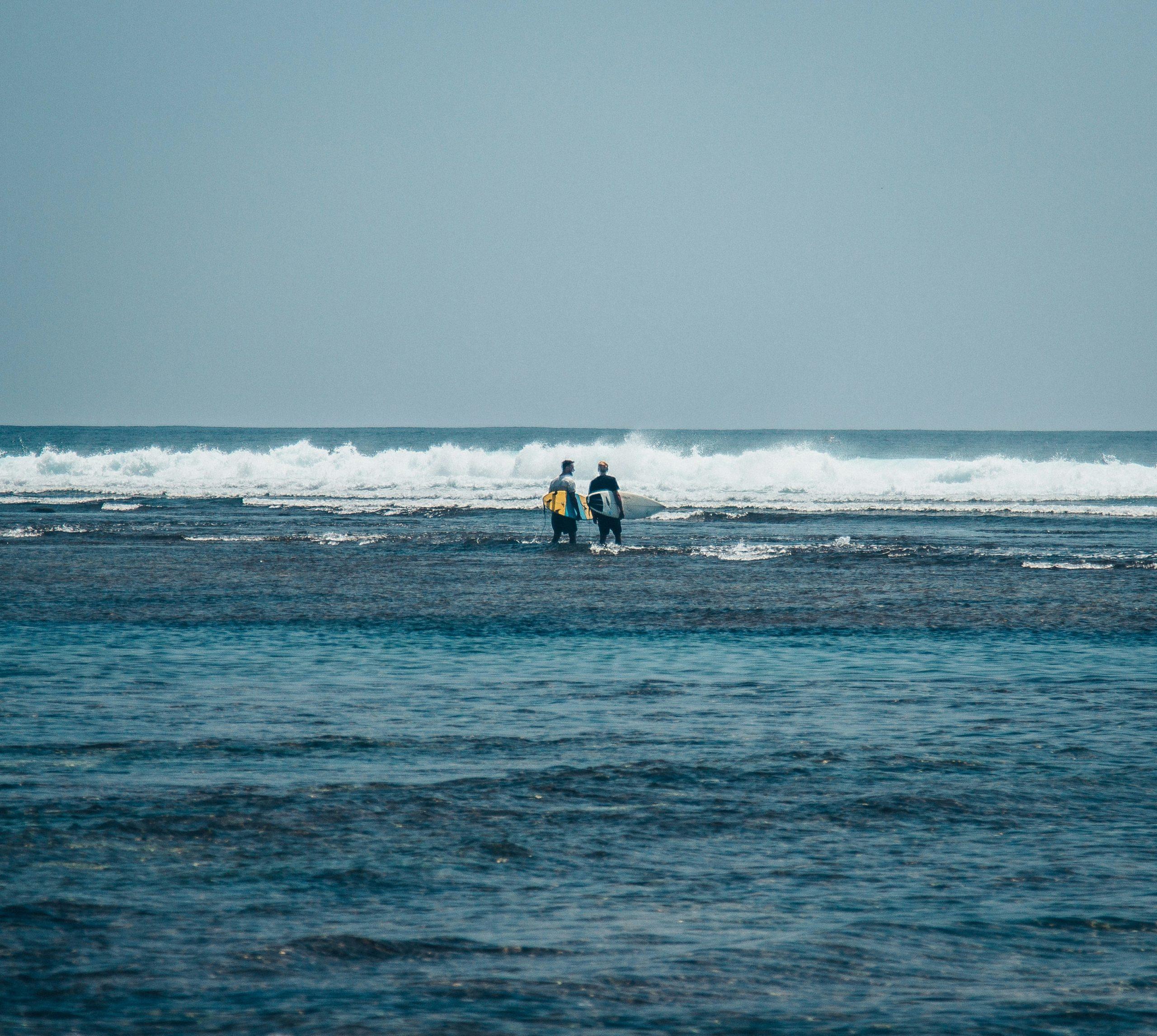 A person rinsing their surfboard luggage with fresh water by the ocean.