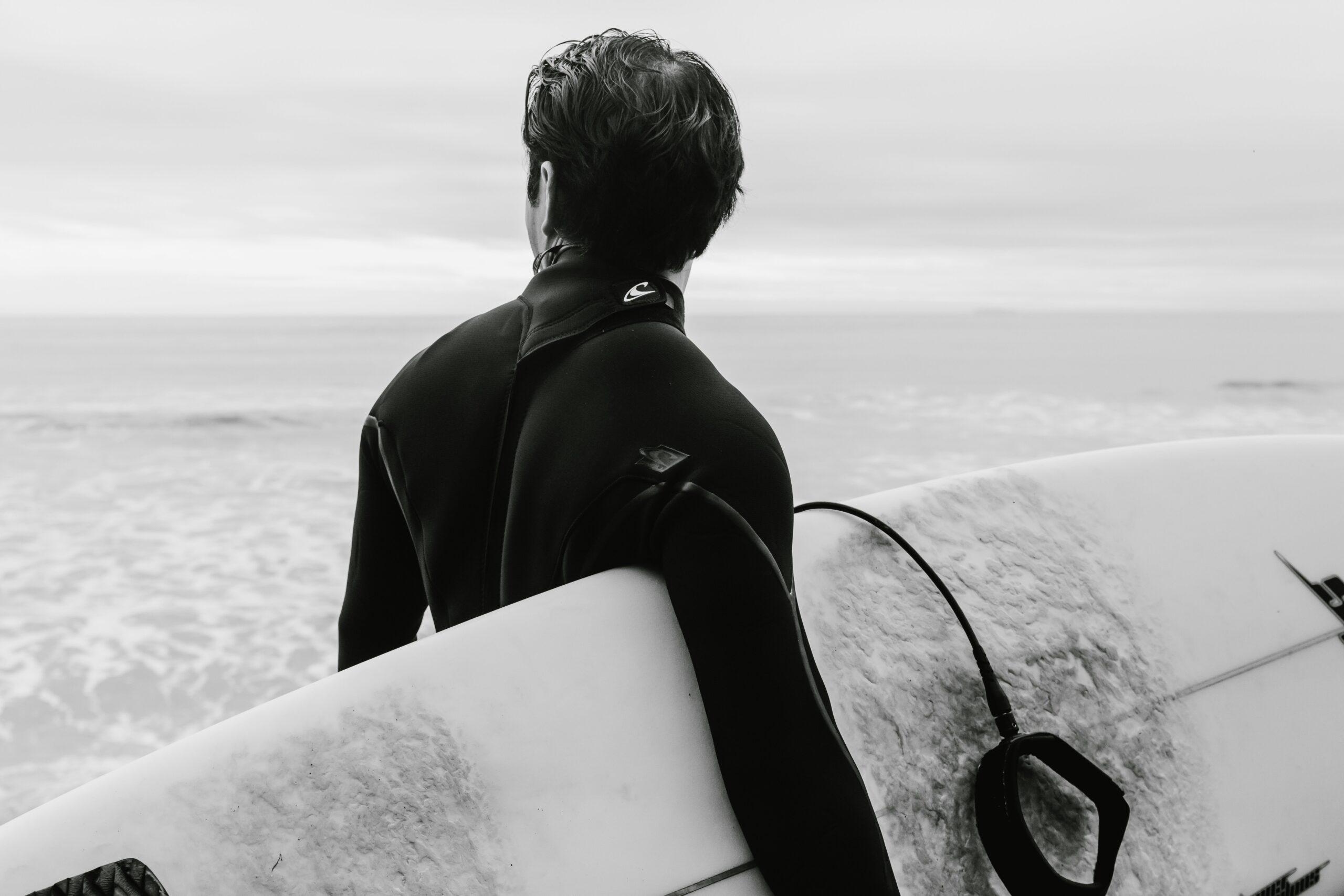 A sleek black water-resistant surfboard bag lying on sand