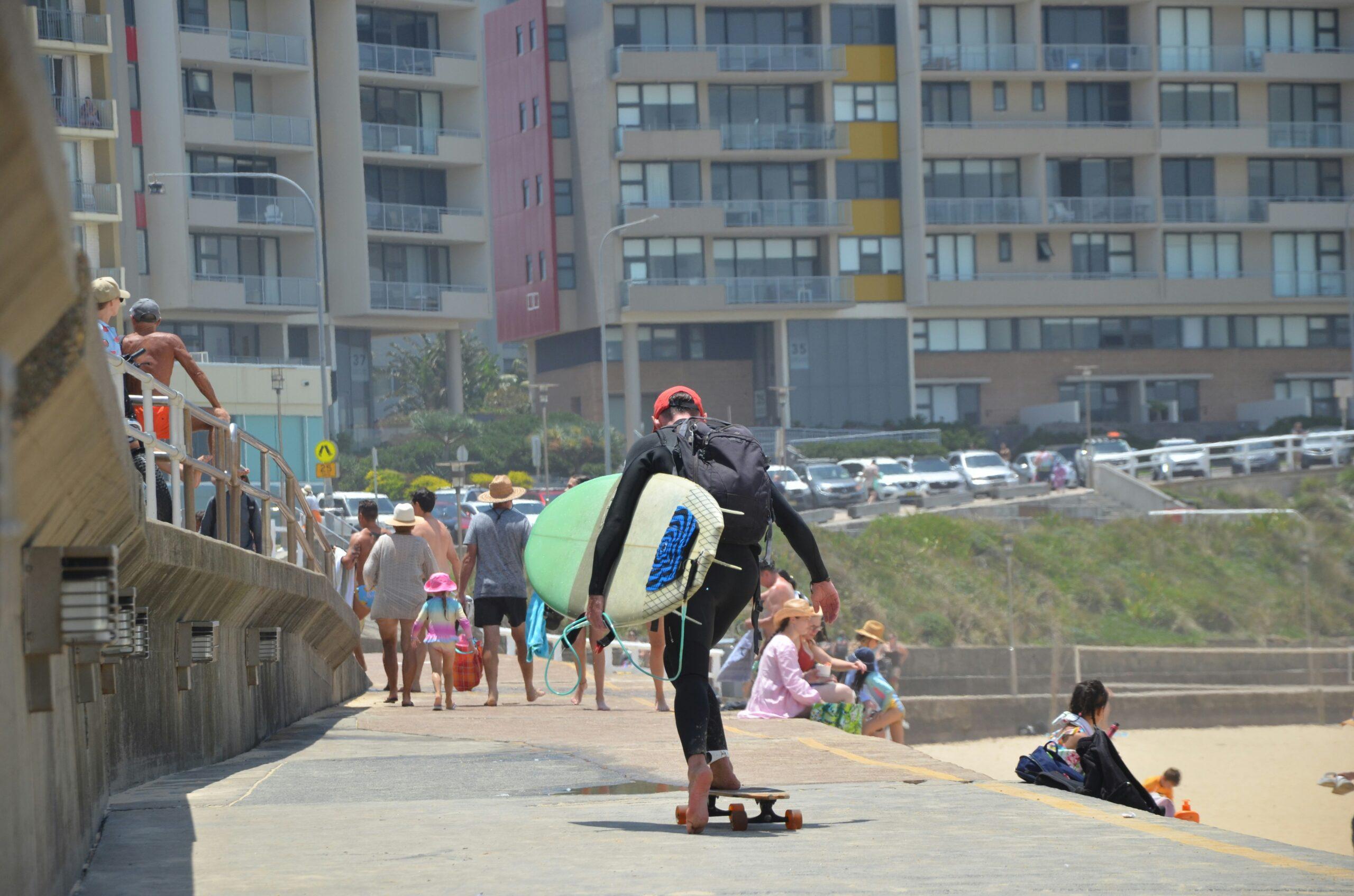 Alex Martinez holding his well-maintained surfboard next to his UV-treated luggage.