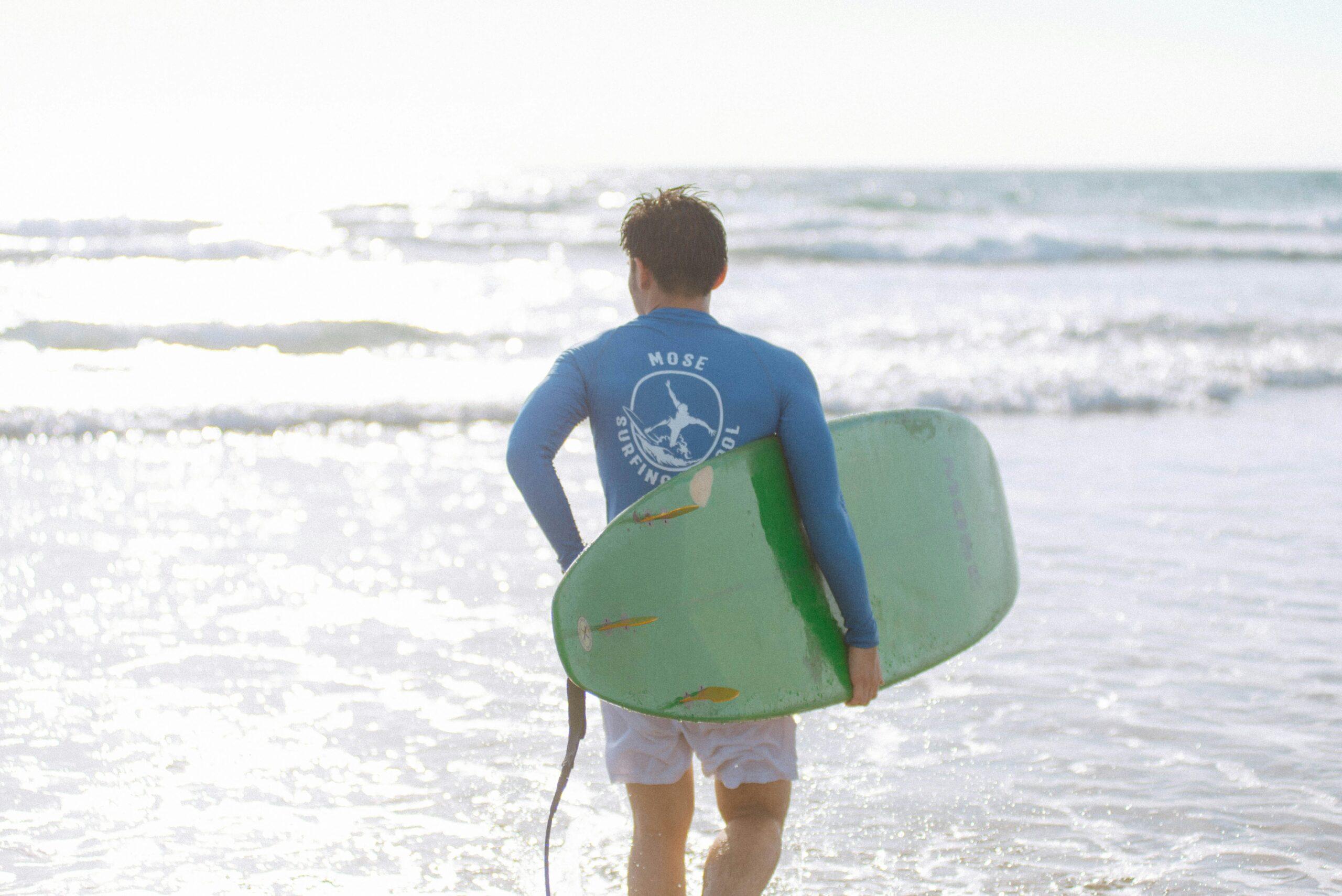 A black hard shell surfboard luggage standing upright on beach sand