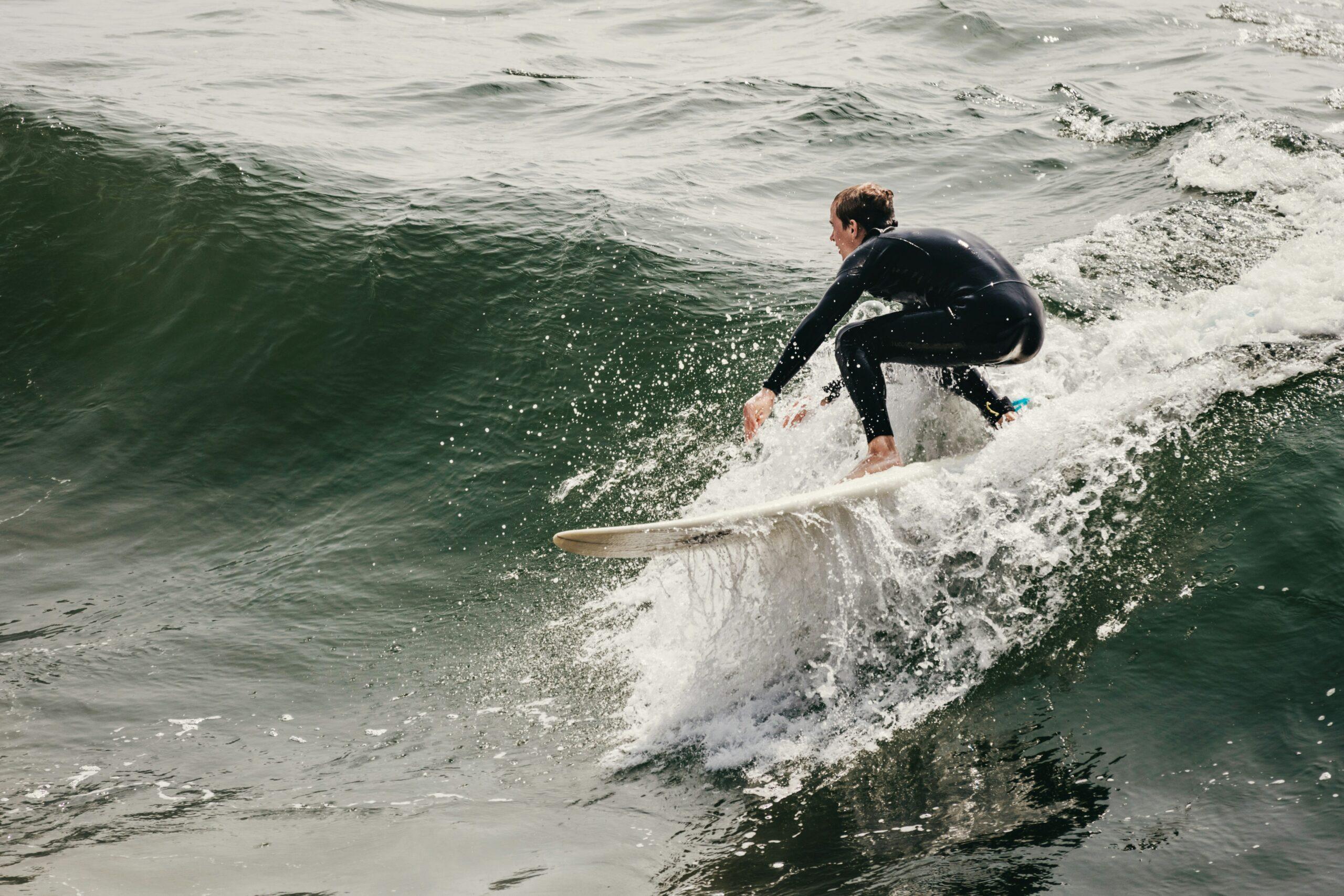 A surfer struggling with a heavy surfboard bag at an airport