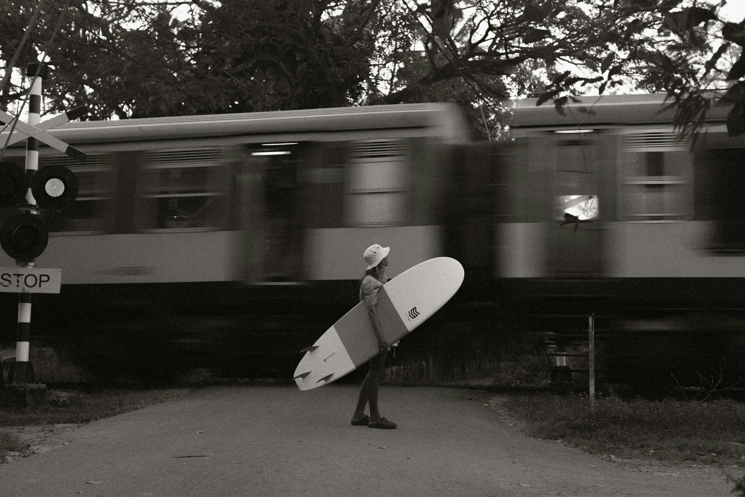 Surfer struggling with a large surfboard in a crowded train car