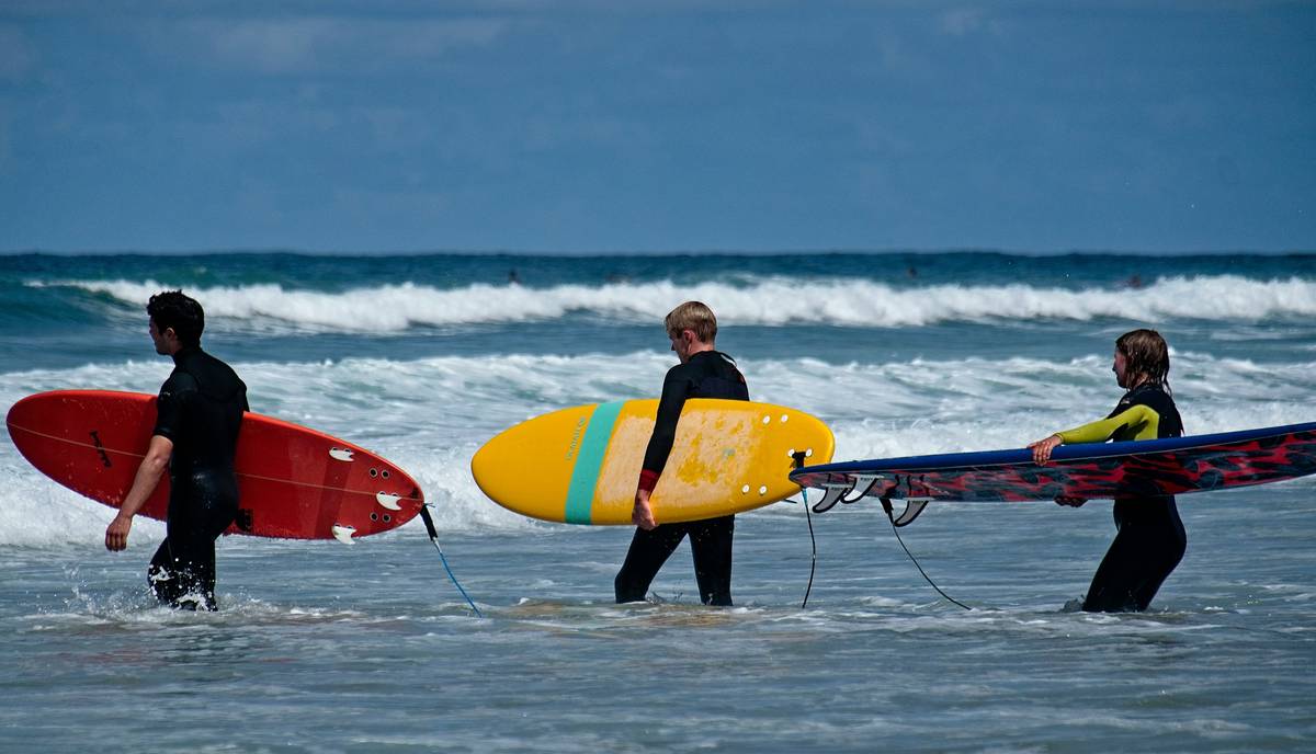 A cracked surfboard beside its damaged luggage case