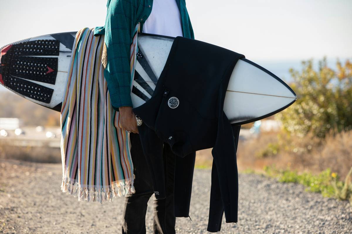 Happy surfer holding his surfboard next to his reliable surf carrier