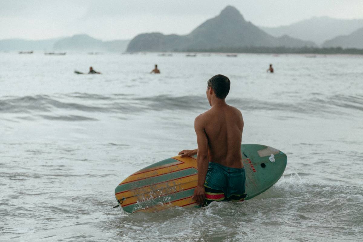 Person measuring a surfboard with a tape measure