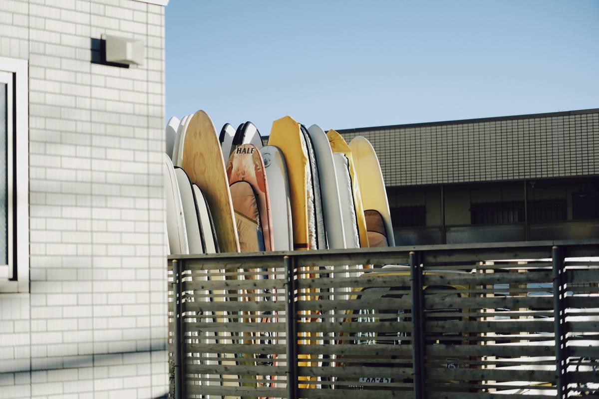 Professional surfer John Doe holding his intact surfboard next to a heavily scuffed secure surfboard vault.