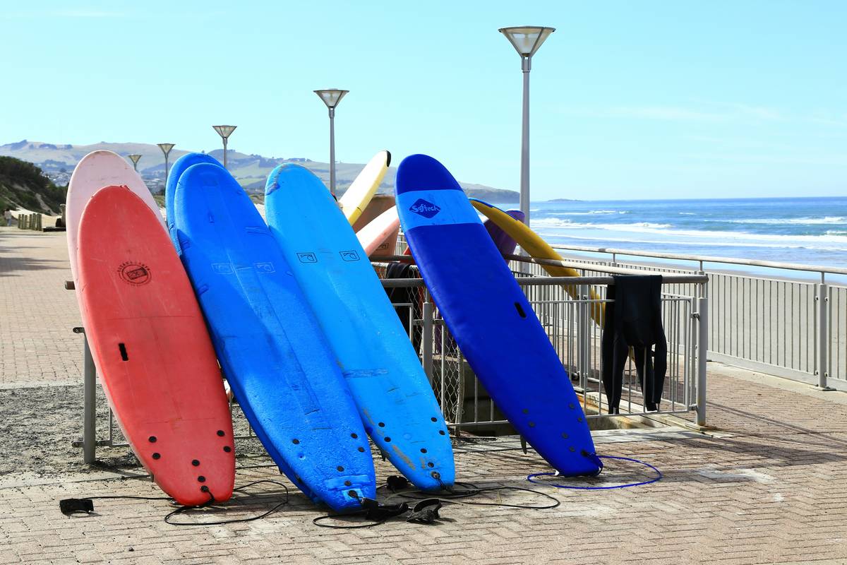 Surfer posing happily with undamaged longboard upon arrival at destination airport