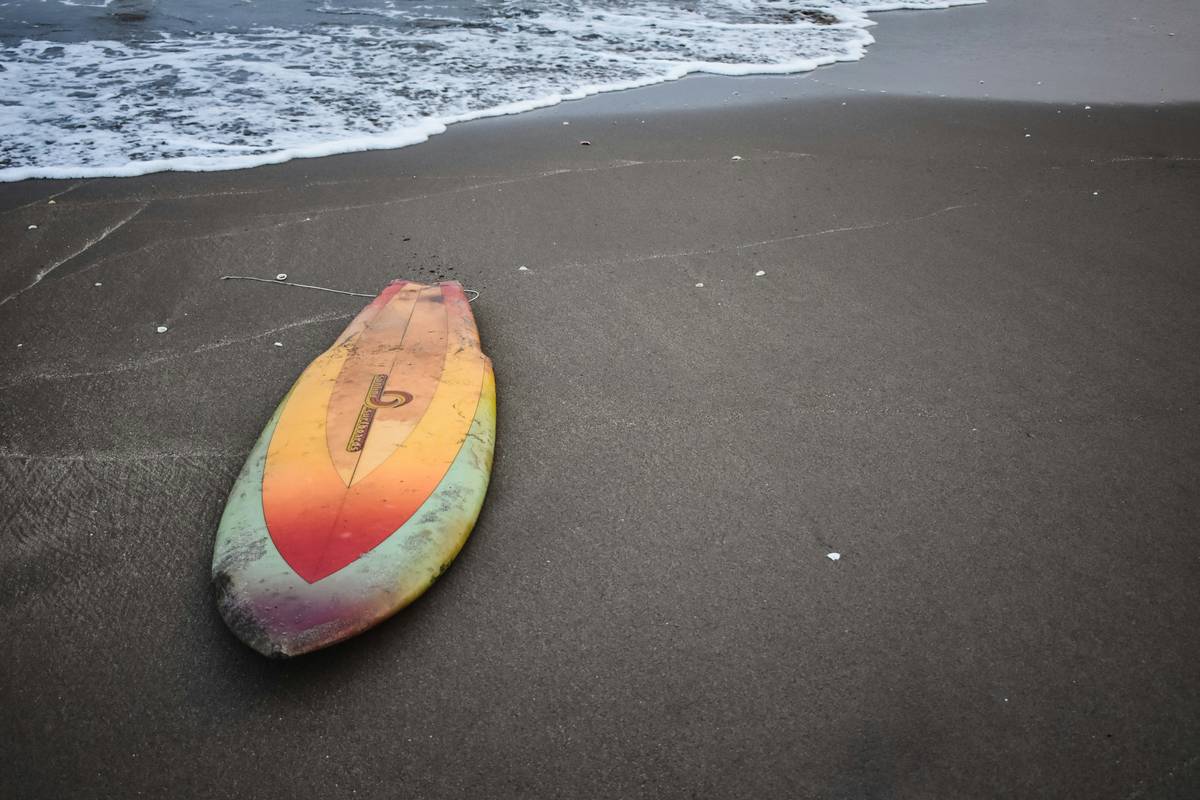 A happy surfer standing next to undamaged surfboards on a beach